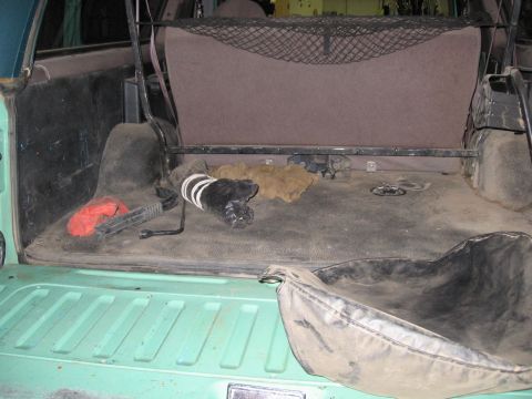1996 Ford Bronco - The cargo area of the vehicle shows a spare tire tool and a red object on the floor.