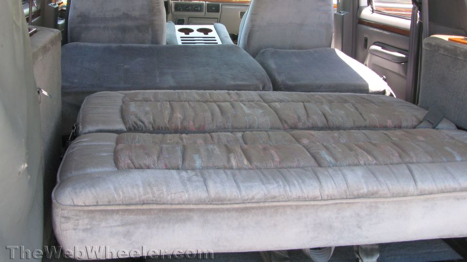 Gray velour rear seats folded flat into a bed inside a conversion truck cabin