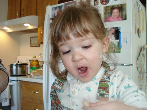 2000 Ford Crown Victoria - A young child with flour on their face is in a kitchen, looking down with their mouth open.