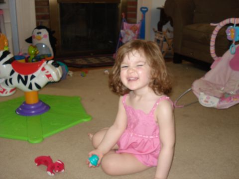 2000 Ford Crown Victoria - A child sits on the floor surrounded by toys, smiling widely.
