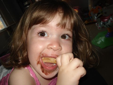 2000 Ford Crown Victoria - A young child with chocolate smeared around her mouth eats a popsicle stick.