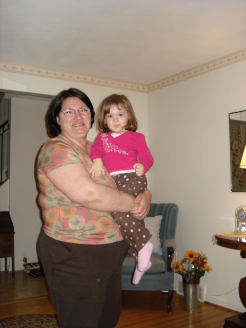 2000 Ford Crown Victoria - A woman holds a small child in her arms inside a room with furniture and decorations.