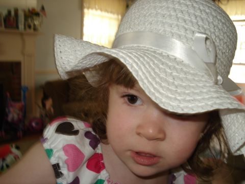 2000 Ford Crown Victoria - A young child is pictured wearing a white sun hat and a dress adorned with colorful hearts.