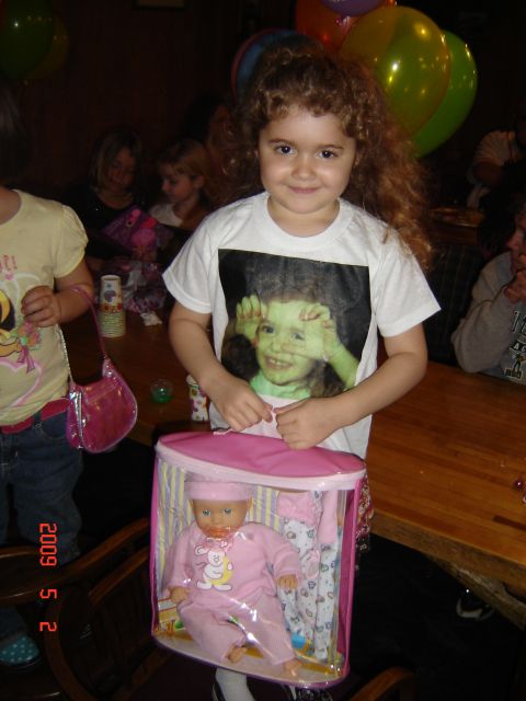 1993 Ford Bronco - A young girl smiles while holding a doll in a pink carrier, with balloons and other children in the background.