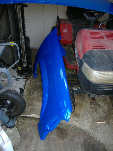 1992 Dodge Dakota - A blue fender is stored in a garage next to a red lawnmower and other equipment.