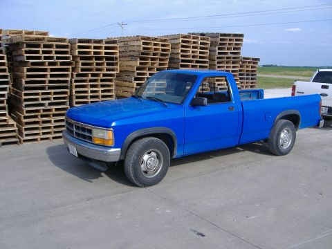 1992 Dodge Dakota - A bright blue 1992 Dodge Dakota pickup truck is seen from a three-quarter front view, parked outdoors near stacks of wooden pallets.