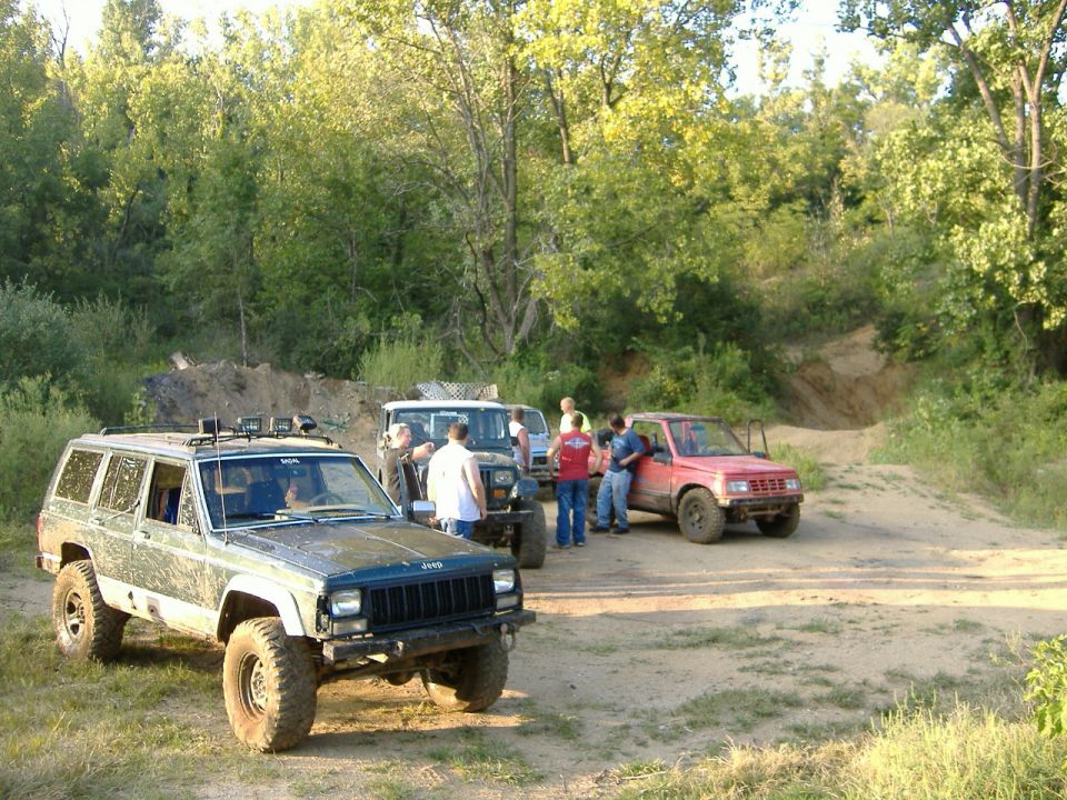 1993 Jeep Cherokee and other off-road vehicles with people gathered around in a dirt lot