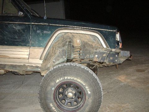 1993 Jeep Cherokee - A muddy 1993 Jeep Cherokee is shown from the front quarter angle, highlighting its off-road condition.