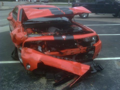 1996 Ford Bronco - Damaged orange sports car with front end crumpled and hood open.