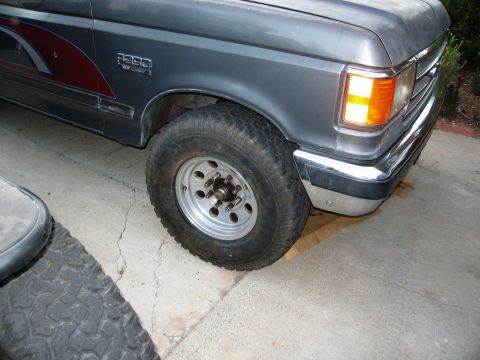 1986 Ford Bronco - Front corner of a gray Ford F-250 truck, showing the fender, wheel, and chrome bumper.