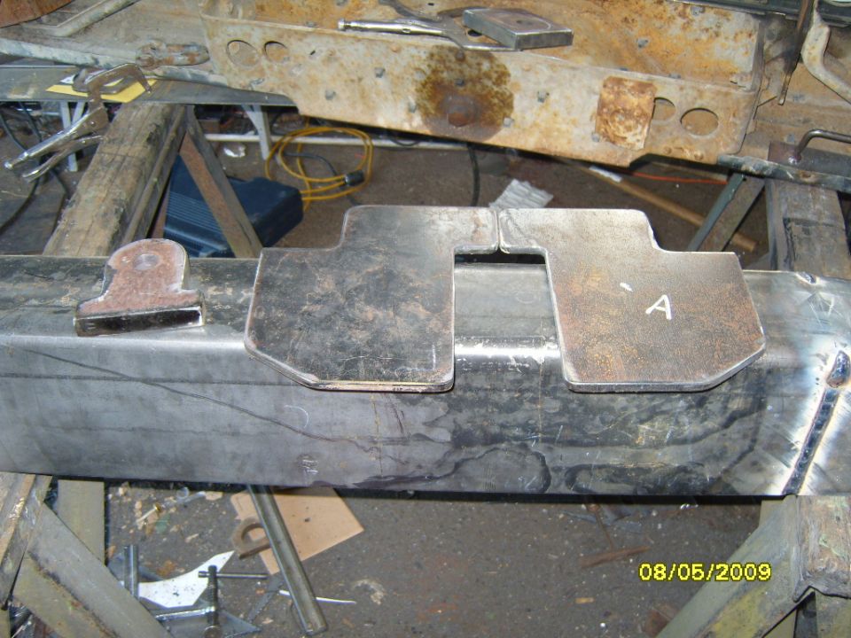 Custom metal brackets being welded onto a vehicle frame, possibly for a bumper. One bracket is marked with an 'A'