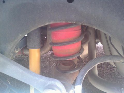 2000 Mercury Grand Marquis - Undercarriage view shows suspension components including a red air spring and a yellow shock absorber.