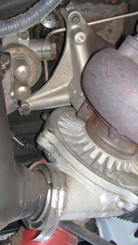 1996 Ford C-350 (Centurion Conversions) - Turbocharger assembly with exhaust manifold and bracket, part of an engine.