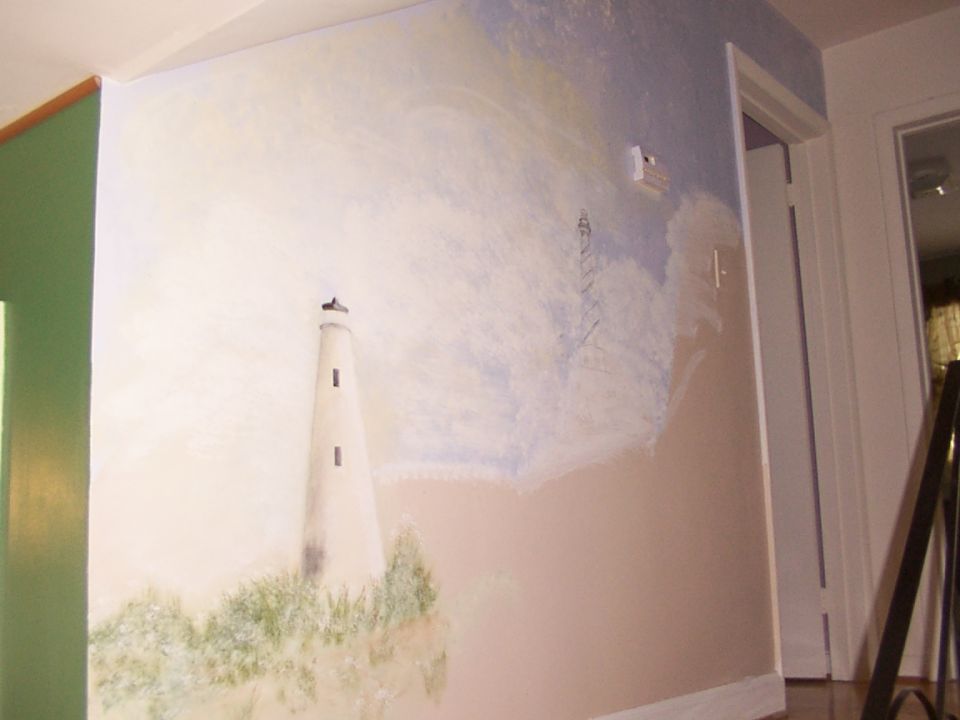 Mural of a lighthouse on a grassy cliff under a cloudy sky, with a green door on the left and a doorway on the right