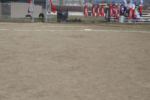 1990 Chevrolet Suburban - A view of a softball field, including the dugout area and fencing, under an overcast sky.
