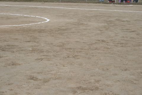 1990 Chevrolet Suburban - A dirt field with white lines, likely for a sports game, in the background people are visible.