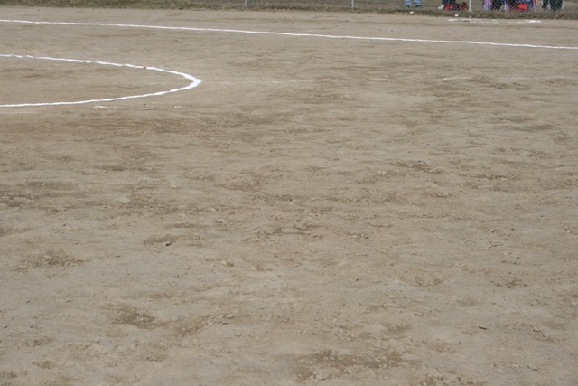 Dirt field with white markings for a sports game, possibly softball or baseball