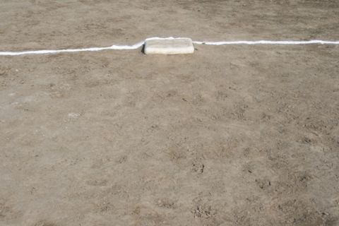 1990 Chevrolet Suburban - A baseball base sits on a dirt infield next to a white foul line.