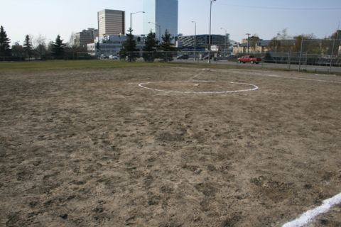 1990 Chevrolet Suburban - A baseball field is shown with a city skyline in the distance and a red truck driving by.