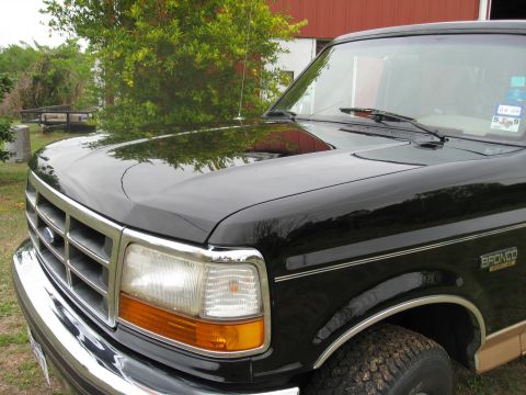 1994 Ford Bronco - A black 1994 Ford Bronco is viewed from the front quarter, showing its distinctive grille and badging.