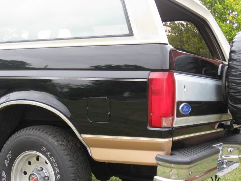 1994 Ford Bronco - Close-up of the rear quarter panel of a Ford Bronco, highlighting its two-tone paint and iconic badge.