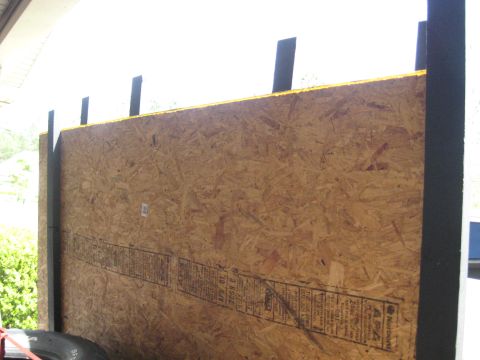 1900 Ford C-350 (Centurion Conversions) - A temporary plywood wall with black trim and a yellow edge is shown, obscuring the view of any potential vehicle.