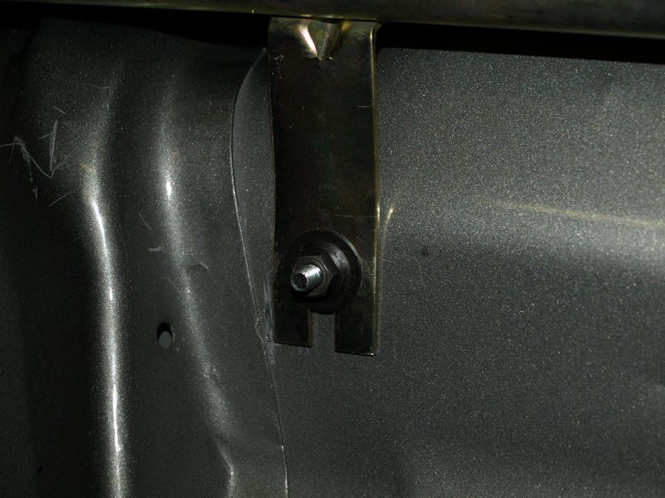 Close-up of a metal bracket secured by a bolt and nut to a textured surface