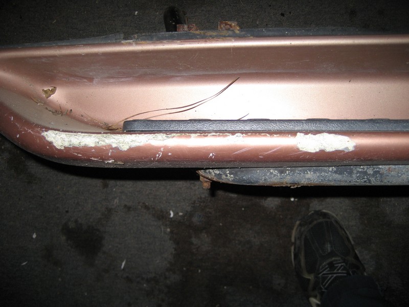 Rose gold vehicle body panel with chipped paint and visible rust
