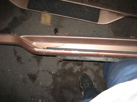 1995 Ford Bronco - Close-up of a damaged bronze running board, likely from a truck or SUV, showing scuffs and a crack.