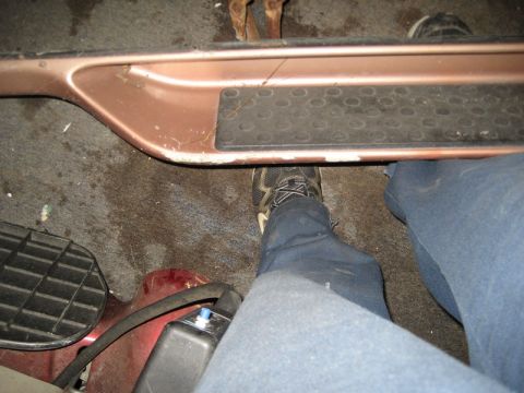 1995 Ford Bronco - Interior view of vehicle pedals and door sill, with a person's legs and feet visible.