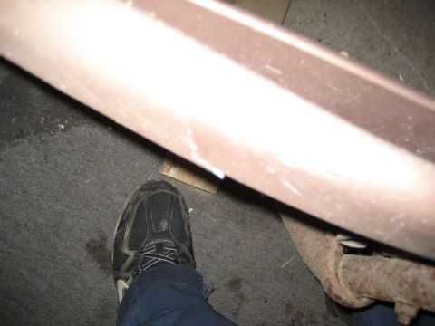 1995 Ford Bronco - A close-up shot focuses on a rusty exhaust pipe and a section of a car's body panel.