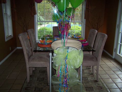 1978 Ford Bronco - A dining table is set with colorful plates and a large balloon arrangement, with chairs around it.