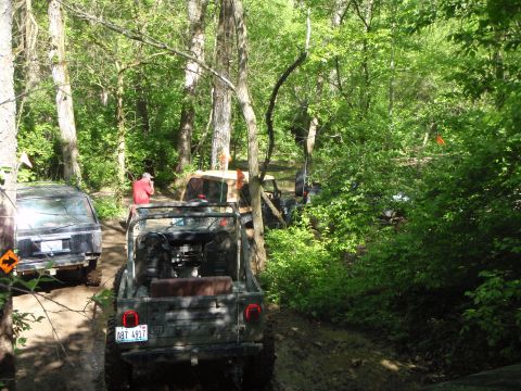 1996 Ford Bronco - Several Jeeps navigate a muddy, wooded trail during an off-road excursion.