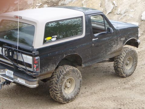 1996 Ford Bronco - This lifted Ford Bronco, seen from a 3/4 front angle, is heavily muddied from off-road use.