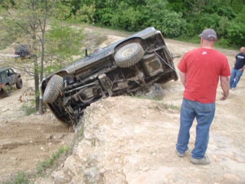 1996 Ford Bronco - This vehicle is on its side after an off-road excursion, with onlookers observing the situation.