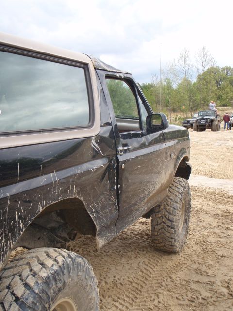 1996 Ford Bronco - A black 1996 Ford Bronco is shown from the side and front quarter angle, lifted with large off-road tires on a sandy surface.