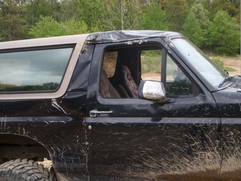 1996 Ford Bronco - Mud-splattered 1996 Ford Bronco with a tan removable top is parked outdoors.