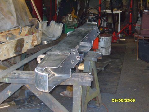 1989 Ford Bronco - A fabricated metal bumper part is shown resting on sawhorses in a workshop setting.