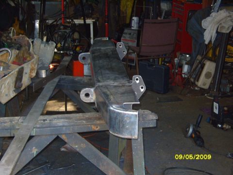 1989 Ford Bronco - Metal bumper part is on a workbench in a garage setting with tools in the background.
