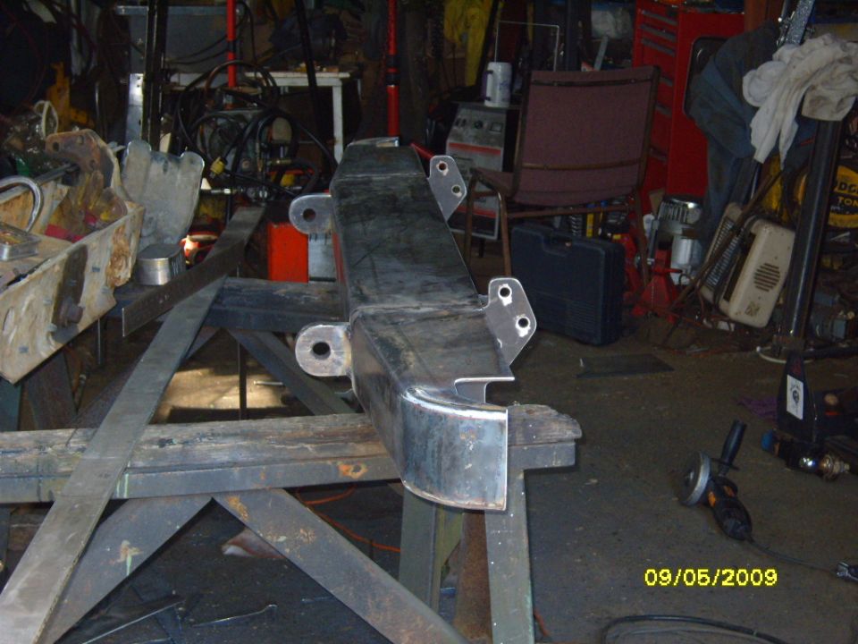 Metal bumper section with mounting holes on a workbench in a garage