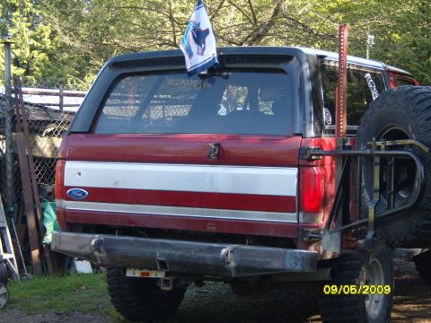 1989 Ford Bronco - Rear view of a red and silver Ford Bronco with a custom bumper and spare tire mount.
