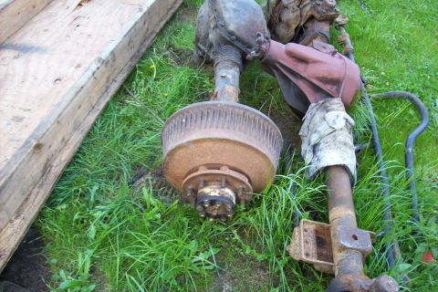1995 Ford Bronco - Two vehicle axles, likely from a truck or SUV, are shown resting on grass.