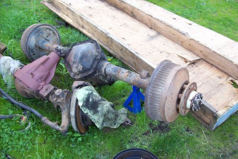 1995 Ford Bronco - Two Ford Bronco rear axles are shown outdoors, one resting on a blue jack stand.