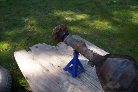 1995 Ford Bronco - A disassembled rear axle assembly rests on a wooden surface in a grassy area.