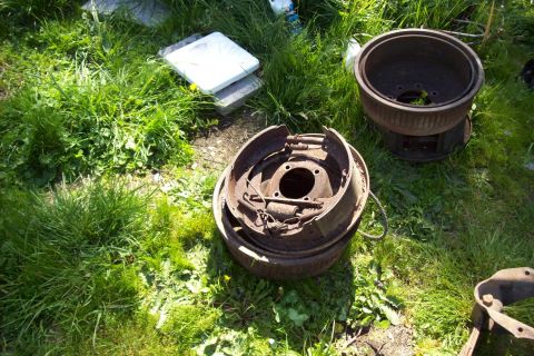 1995 Ford Bronco - Discarded brake parts sit on the grass, showing signs of rust and wear.