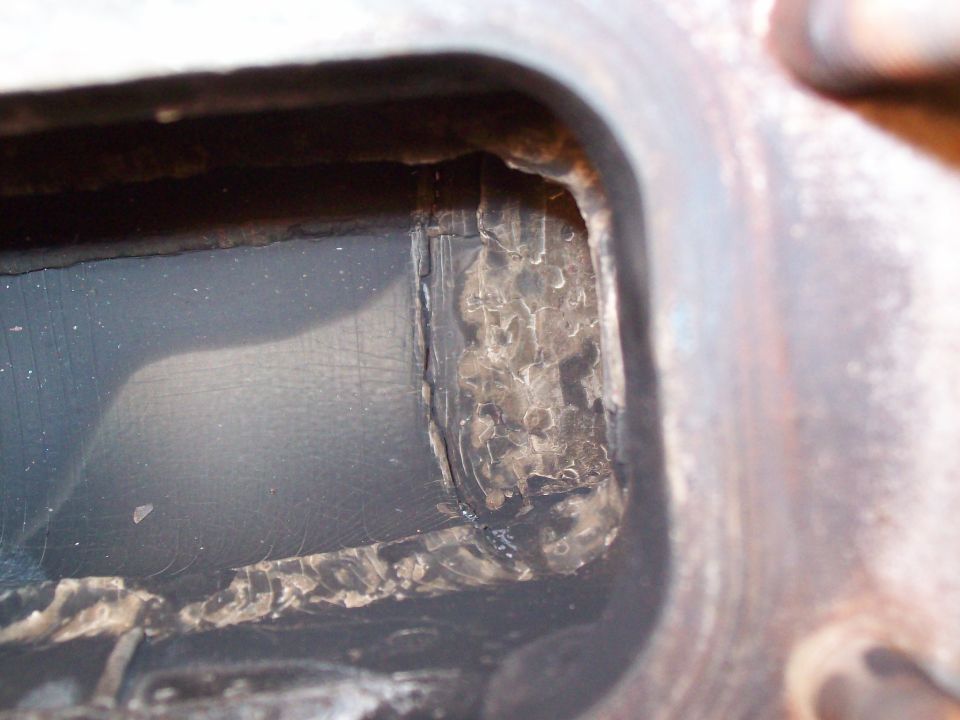 Close-up of a corroded exhaust manifold interior with visible damage and residue