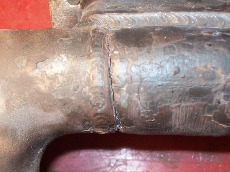 Close-up of a welded metal exhaust pipe with visible weld marks and some rust