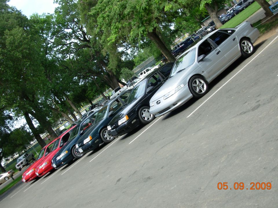 Several sedans parked in a row, including a silver 1995 Ford Taurus