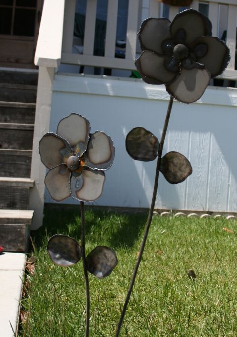 1984 Ford Bronco - Decorative metal flowers stand in a yard, with a house and stairs visible behind them.