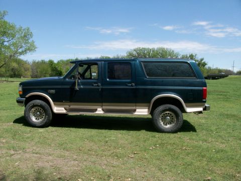 1995 Ford C-350 (Centurion Conversions) - Side view of a 1995 Ford C-350 (Centurion Conversions) pickup truck with a camper shell parked on grass.